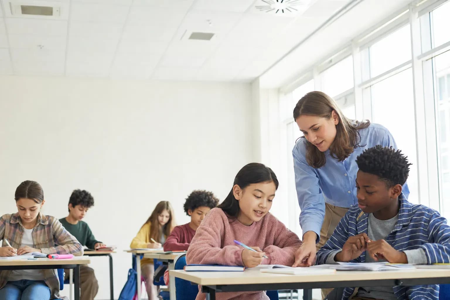 Pupils and a teacher around a table in a bright classroom